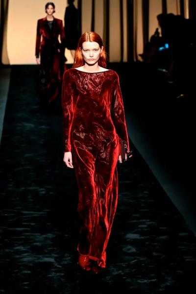 Модель в длинном бархатном платье красного цвета с длинными рукавами